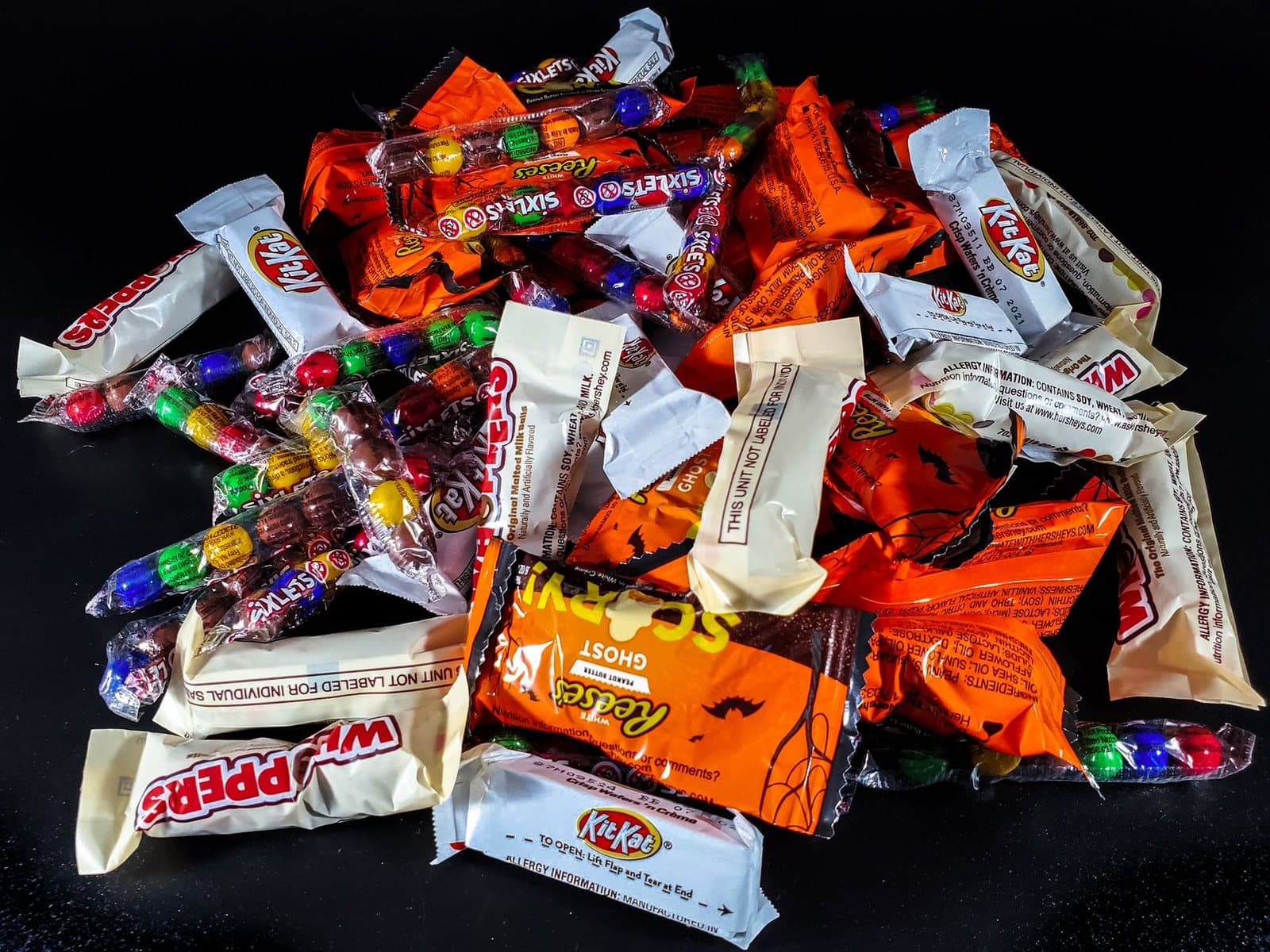 A vibrant pile of assorted Halloween candies, including chocolate bars and sweets, perfect for trick-or-treat fun.